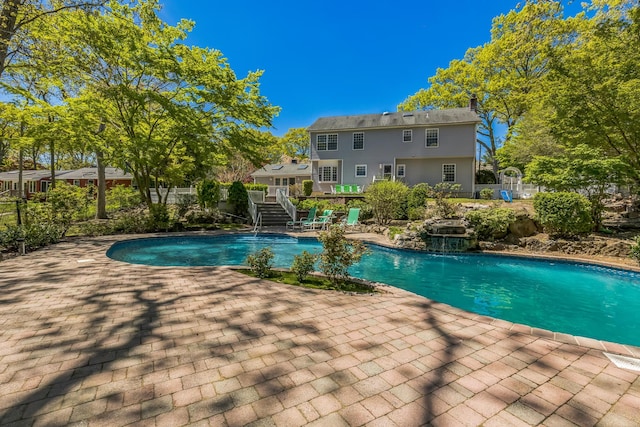 pool featuring fence, a patio area, and stairway