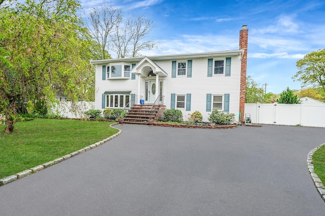 split foyer home with a chimney, driveway, and a gate
