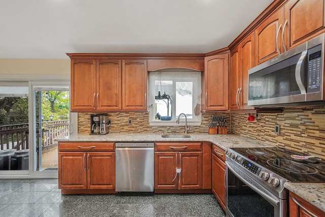 kitchen featuring stainless steel appliances, a sink, tasteful backsplash, and light stone counters