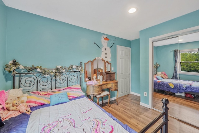 bedroom with wood finished floors, a closet, baseboards, and recessed lighting