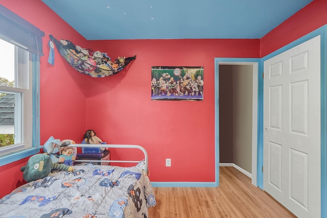bedroom with wood finished floors, multiple windows, and baseboards