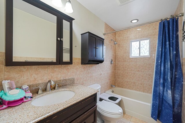 full bath with tile walls, shower / tub combo, toilet, vanity, and tile patterned flooring