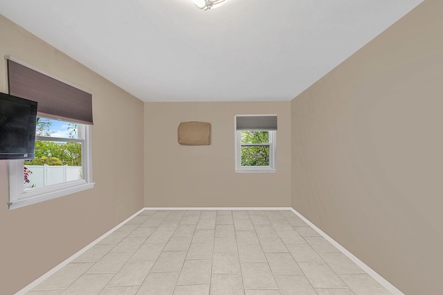 spare room featuring healthy amount of natural light, baseboards, and light tile patterned floors