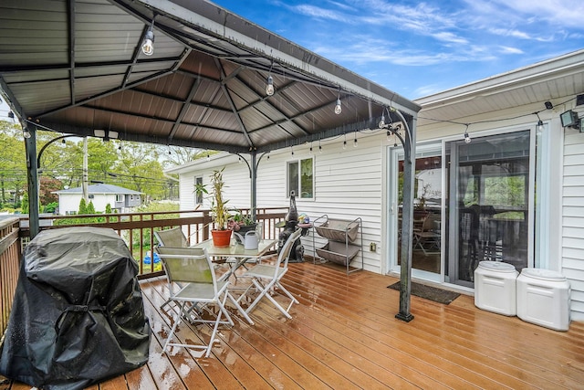 wooden terrace with a gazebo, a grill, and outdoor dining area