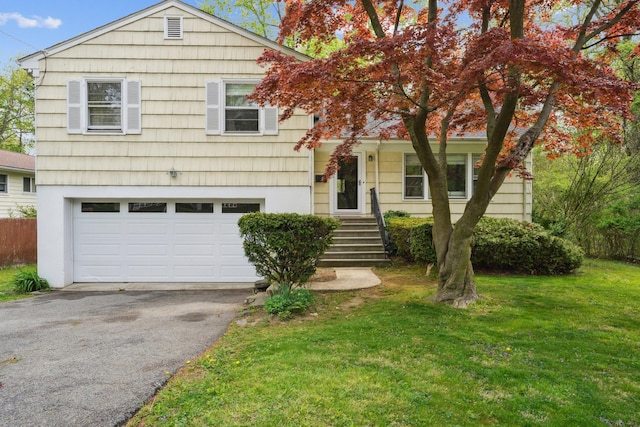 split level home featuring a front yard, aphalt driveway, a garage, and fence