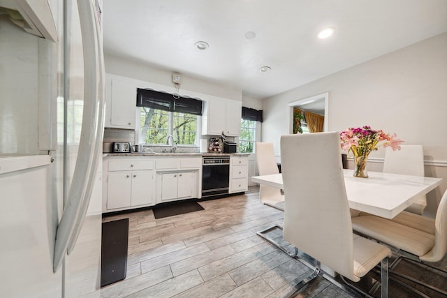 kitchen with light countertops, white cabinets, a sink, and dishwasher