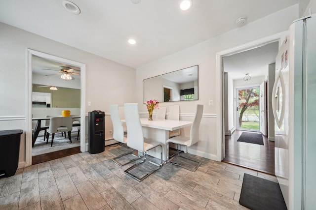 dining area with ceiling fan, a baseboard radiator, light wood-type flooring, and recessed lighting