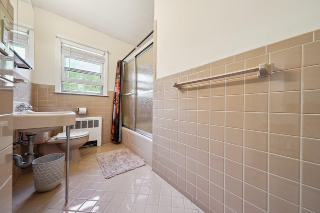bathroom featuring tile walls, toilet, enclosed tub / shower combo, radiator heating unit, and tile patterned flooring