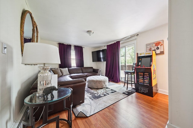 living room with baseboards, a baseboard heating unit, plenty of natural light, and wood finished floors
