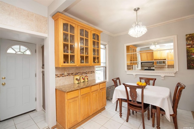 dining space with light tile patterned flooring, a notable chandelier, plenty of natural light, and ornamental molding