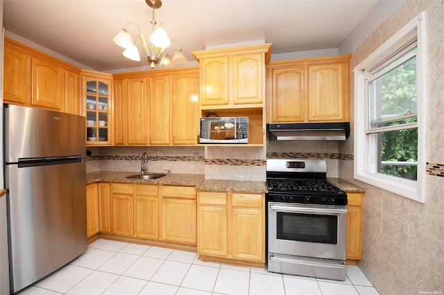 kitchen featuring light stone counters, a sink, under cabinet range hood, and stainless steel appliances