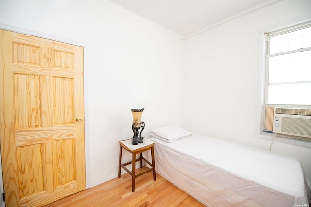 bedroom with cooling unit and wood finished floors