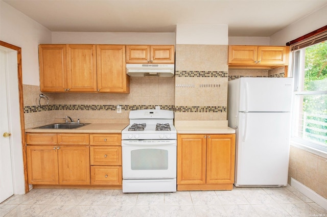 kitchen with white appliances, under cabinet range hood, a sink, and marble finish floor