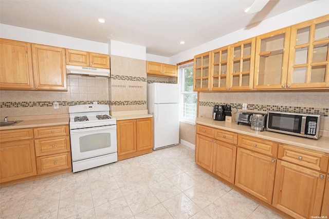 kitchen with decorative backsplash, white appliances, glass insert cabinets, light countertops, and under cabinet range hood