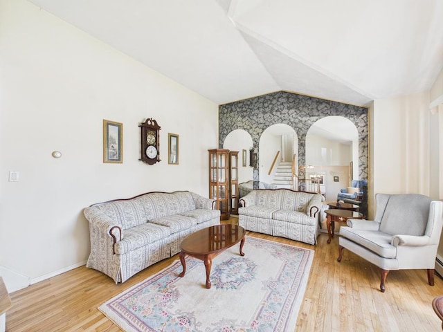 living room with lofted ceiling, arched walkways, hardwood / wood-style flooring, and baseboards