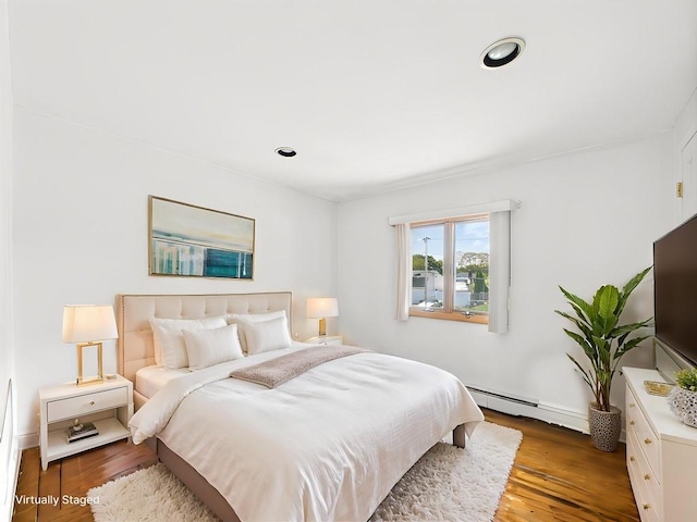 bedroom featuring baseboard heating, wood finished floors, baseboards, and recessed lighting