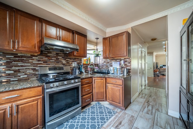 kitchen with under cabinet range hood, gas range, and brown cabinets
