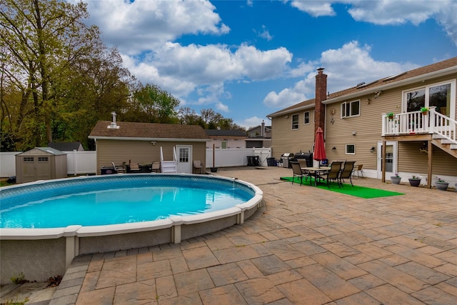 pool with an outdoor structure, area for grilling, fence, a storage unit, and a patio
