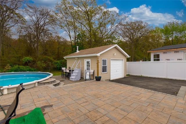 view of pool featuring an outbuilding, fence, a fenced in pool, and a patio