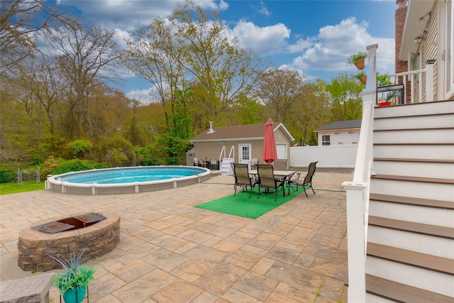 outdoor pool featuring outdoor dining space, fence, a patio, an outdoor structure, and an outdoor fire pit