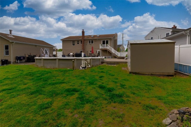 back of house with a lawn, an outdoor pool, a shed, and an outbuilding