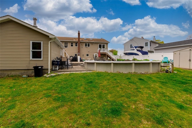rear view of property featuring a lawn, a patio area, an outdoor pool, and a fenced backyard