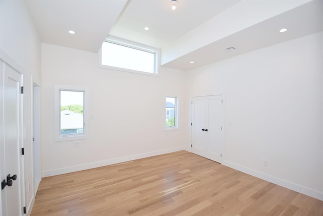 141 Flamingo St, Atlantic Beach, NY 11509 - empty room with healthy amount of natural light, light wood finished floors, a high ceiling, baseboards, and recessed lighting