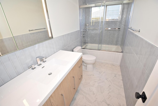 141 Flamingo St, Atlantic Beach, NY 11509 - bathroom with marble look tiles, tile walls, vanity, toilet, and combined bath / shower with glass door