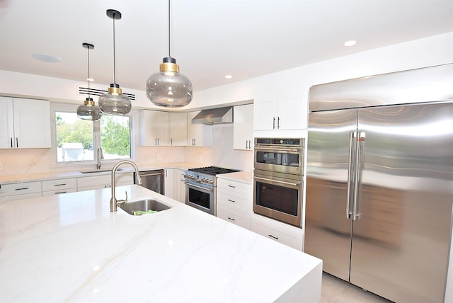 141 Flamingo St, Atlantic Beach, NY 11509 - kitchen with high quality appliances, backsplash, a sink, white cabinetry, and wall chimney range hood