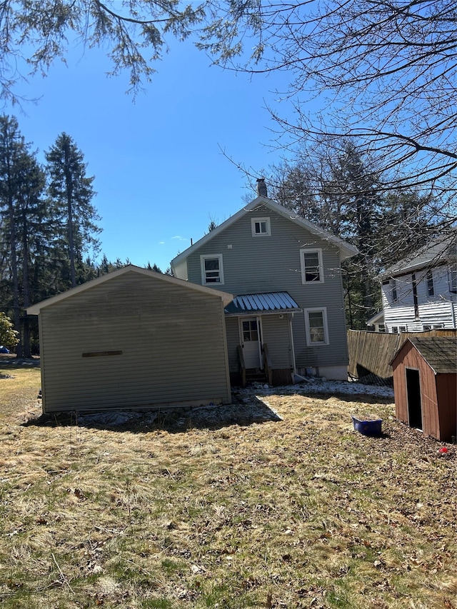 rear view of property featuring an outbuilding, a chimney, and a shed