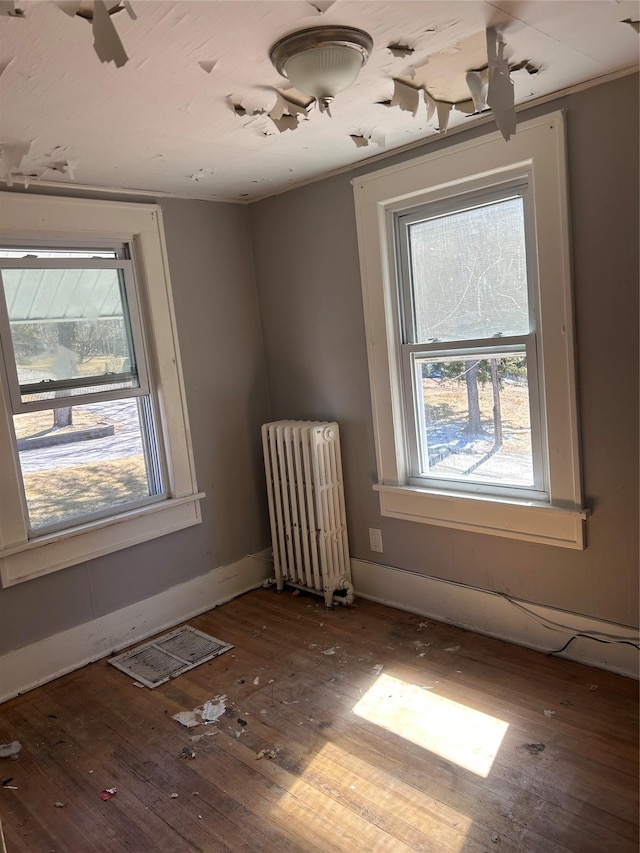spare room with radiator, visible vents, baseboards, and hardwood / wood-style floors