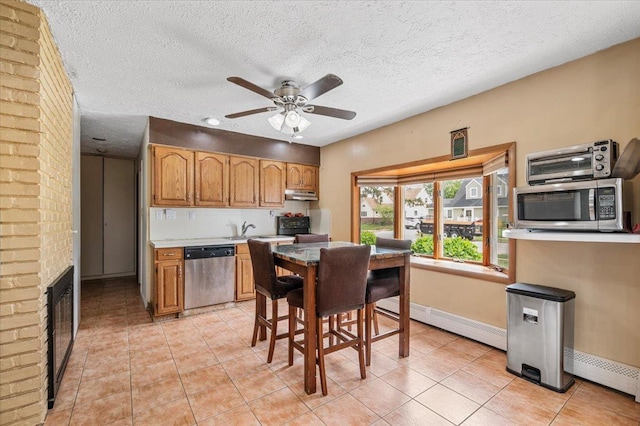 kitchen with appliances with stainless steel finishes, a baseboard heating unit, ceiling fan, under cabinet range hood, and a textured ceiling