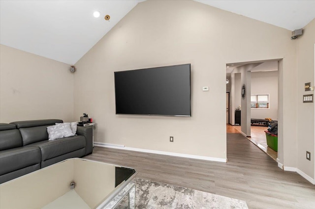 living room featuring wood finished floors, baseboards, and high vaulted ceiling