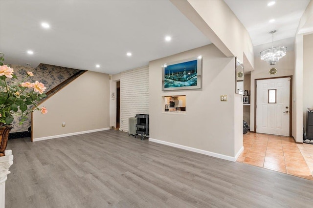 unfurnished living room with baseboards, light wood-type flooring, a chandelier, recessed lighting, and stairs