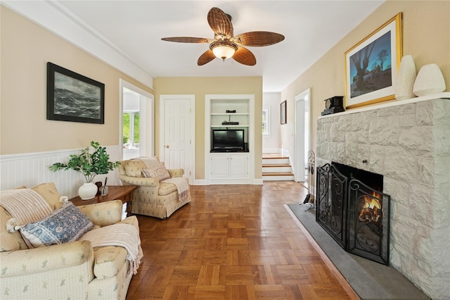 90 Shingle House Rd, Millwood, NY 10546 - living room featuring built in shelves, ceiling fan, a stone fireplace, and wainscoting