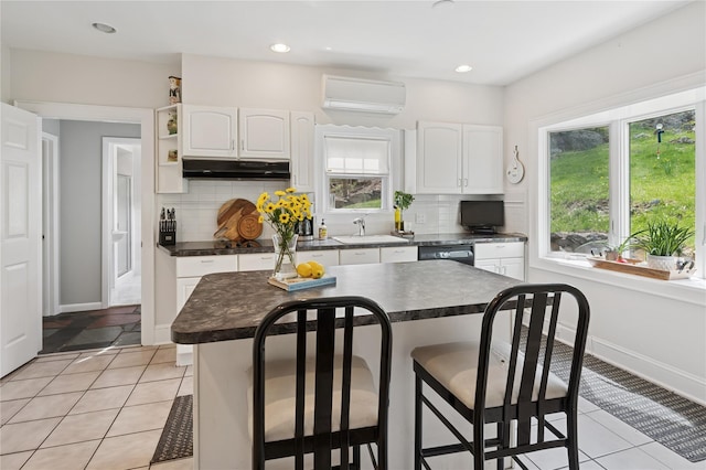90 Shingle House Rd, Millwood, NY 10546 - kitchen with under cabinet range hood, a wall unit AC, dark countertops, a breakfast bar area, and recessed lighting