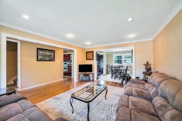 living area featuring wood finished floors, crown molding, baseboards, and recessed lighting