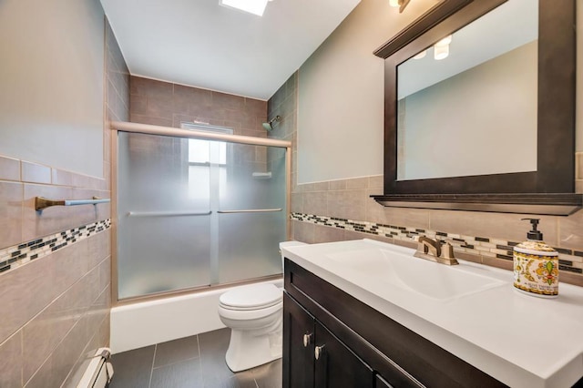 full bath with tile walls, tile patterned floors, toilet, vanity, and shower / bath combination with glass door
