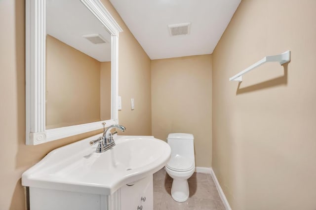 bathroom with toilet, vanity, baseboards, and tile patterned floors
