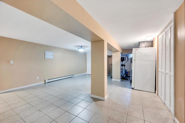 basement featuring freestanding refrigerator, baseboard heating, light tile patterned floors, and baseboards