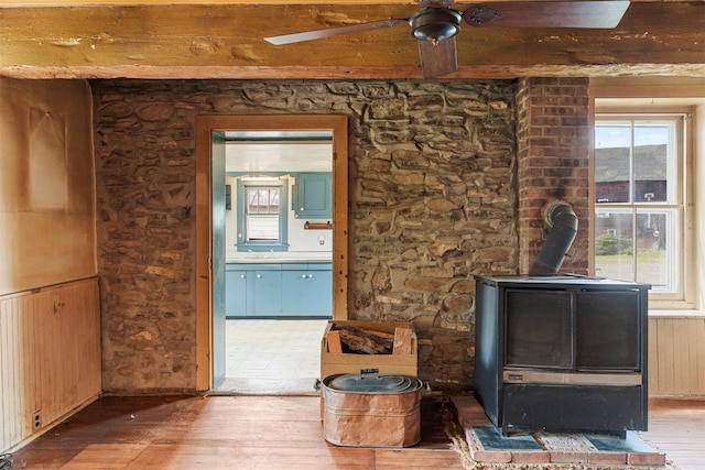 unfurnished living room with a wood stove, a wealth of natural light, and hardwood / wood-style floors