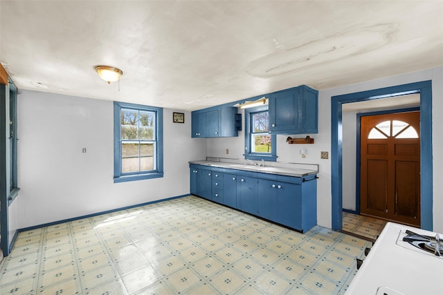 kitchen featuring light countertops, light floors, baseboards, and blue cabinetry