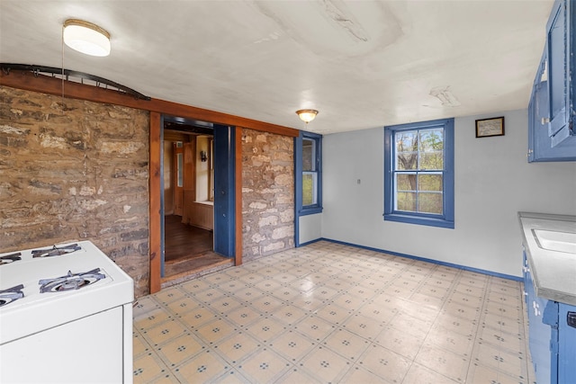 kitchen with a sink, light floors, baseboards, gas range gas stove, and blue cabinetry
