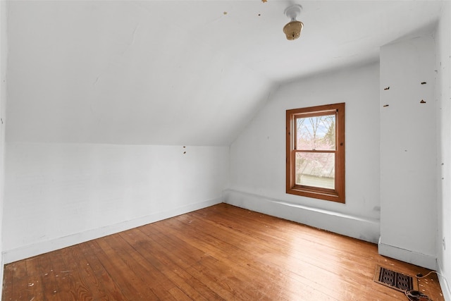 bonus room featuring baseboards, hardwood / wood-style floors, visible vents, and vaulted ceiling