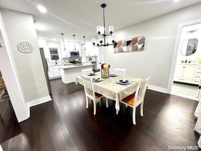 2906 Oceanside Rd, Oceanside, NY 11572 - dining space featuring a chandelier, dark wood-style flooring, and baseboards