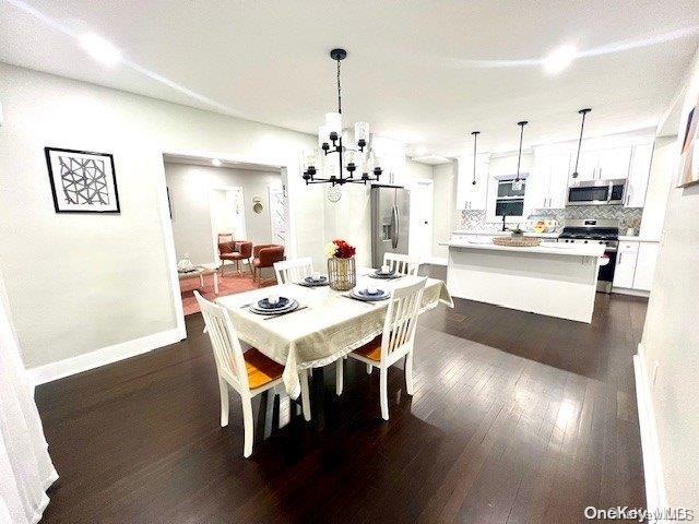 2906 Oceanside Rd, Oceanside, NY 11572 - dining room featuring a chandelier, dark wood finished floors, and baseboards
