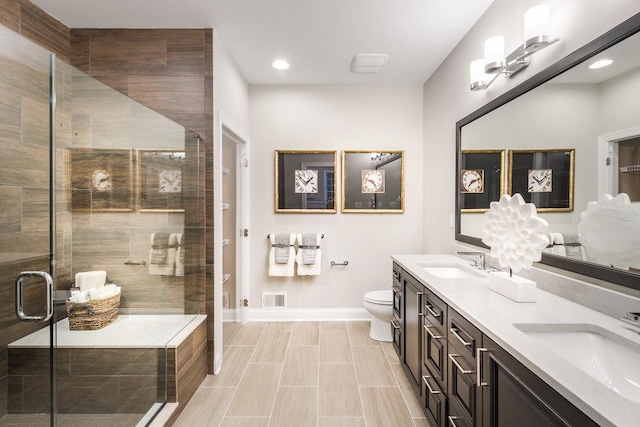 bathroom featuring toilet, a stall shower, baseboards, double vanity, and recessed lighting