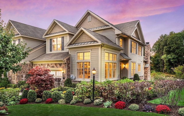 view of front of property with stone siding, a shingled roof, and a standing seam roof