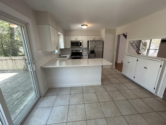kitchen with a peninsula, appliances with stainless steel finishes, a healthy amount of sunlight, and a sink