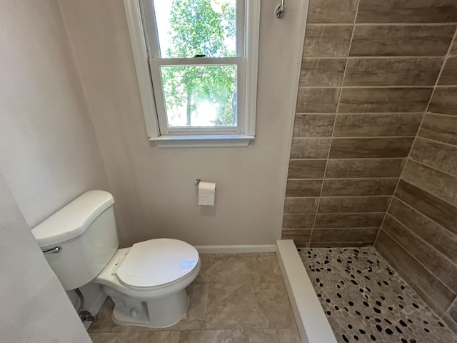 full bath featuring toilet, baseboards, and a shower stall